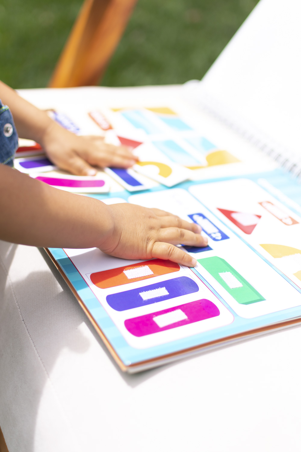 Manos de niña jugando con el libro Jugando a Programar con piezas de velcro para aprender lógica sin pantallas