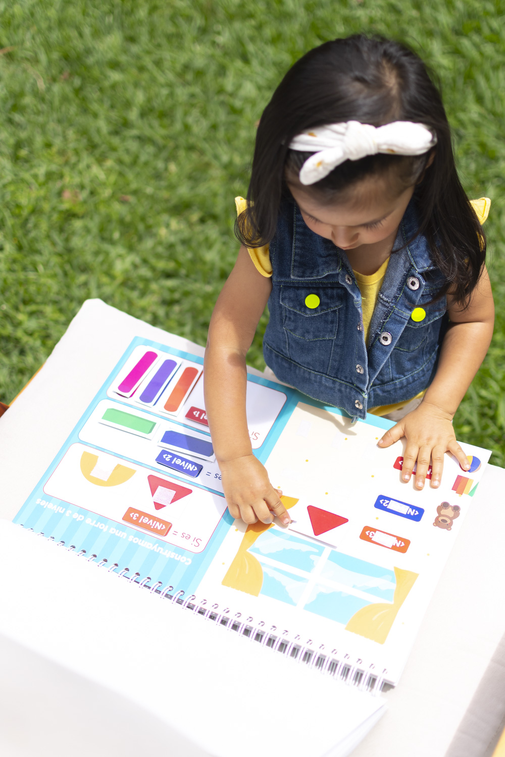 Vista aérea de niña jugando con el libro Jugando a Programar con piezas de velcro para aprender lógica sin pantallas